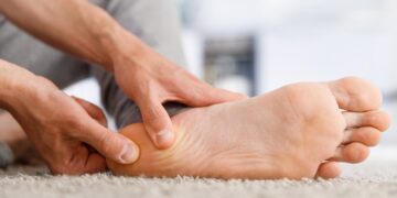 Close up of a man rubbing his heel from plantar fasciitis pain.