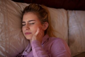 A woman sleeping with TMJ pain that can be treated with chiropractic care.