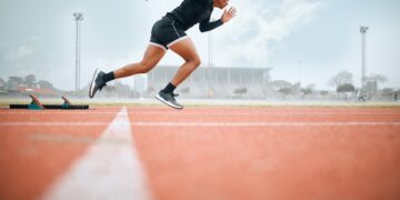 An African American runner practices sprints on a track.