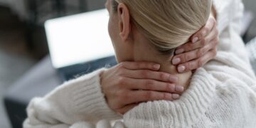 A woman rubs her neck from a pinched nerve.