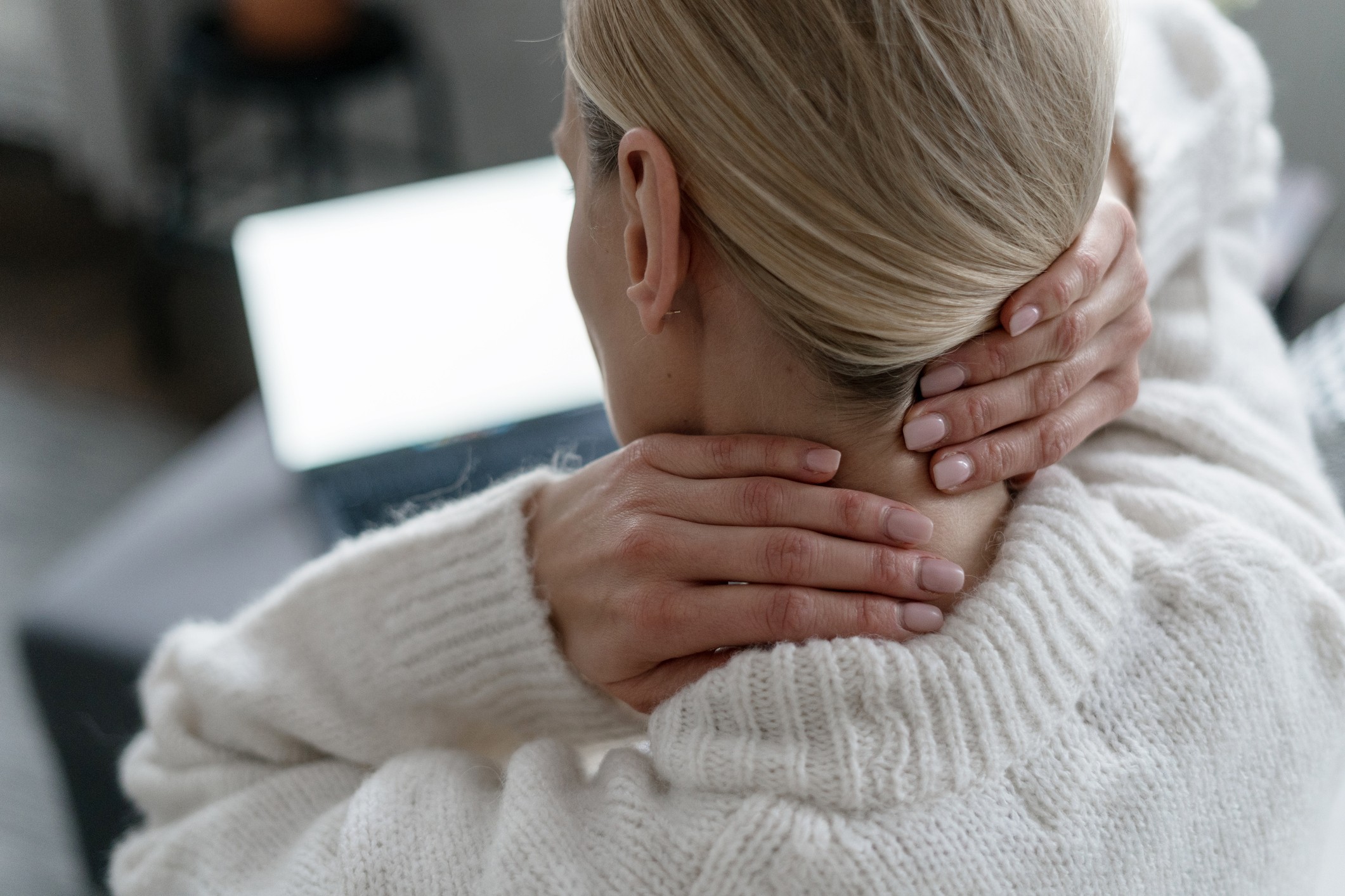 A woman rubs her neck from a pinched nerve.