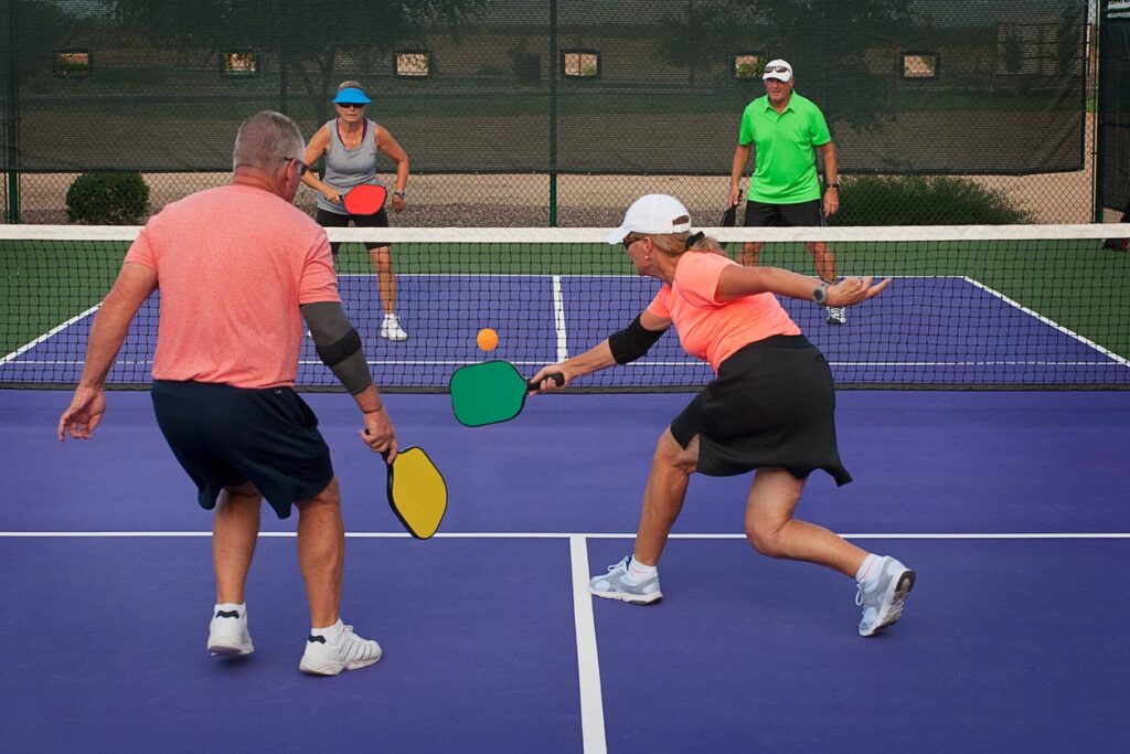 Four older pickleball players on the court in the middle of play. 