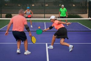 Four older pickleball players on the court in the middle of play.
