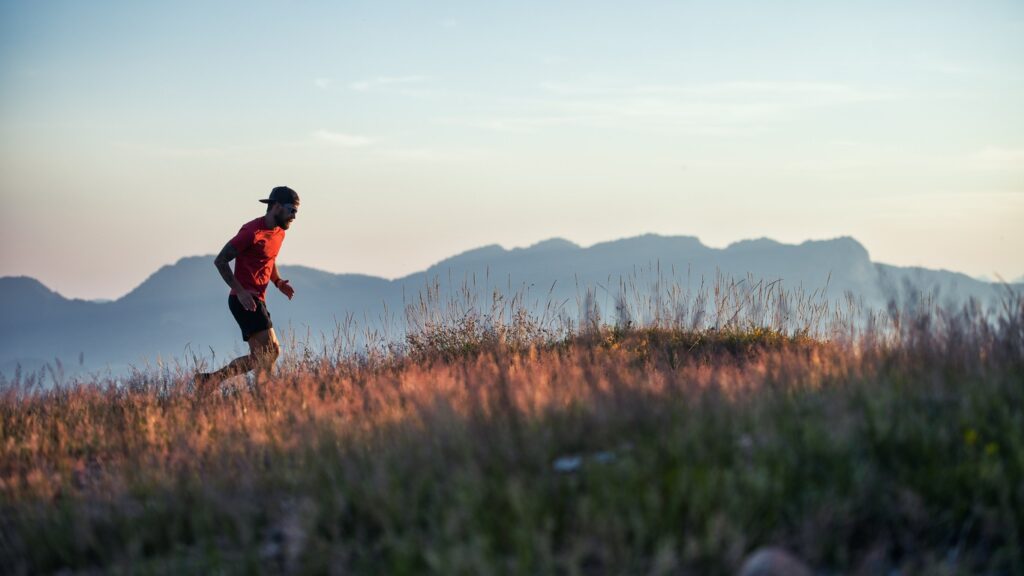 A male trail runner silhouetted against mountains as he runs along a ridge in Bend, Oregon. 