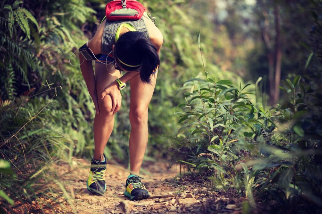 A trail runner grabs her knee in pain while on a trail in Bend, Oregon. 