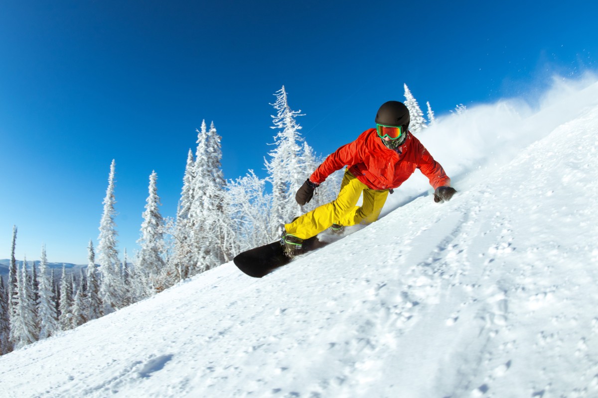 Close up view of a snowboarder carving a turn on a powder run.